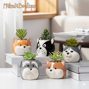 May include: A collection of ceramic dog-shaped planters, each holding a small succulent plant. The planters feature different dog breeds with varying colors, including orange, black, gray, and brown. The text "Malinda Boutiques" is visible in the upper left corner.