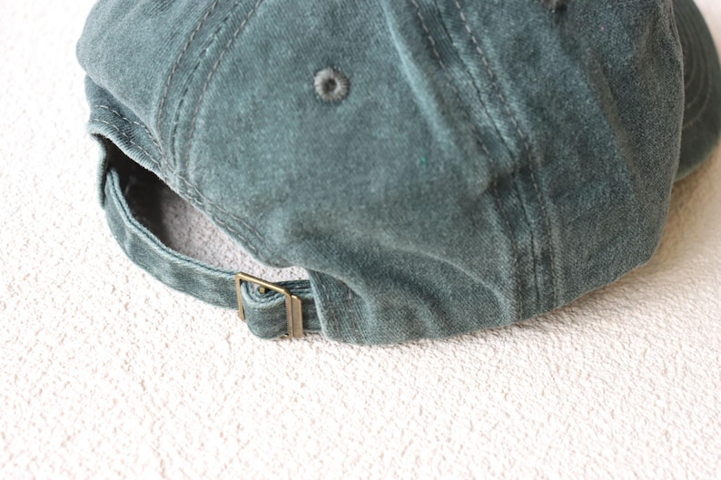 May include: A dark green cotton baseball cap with a brass buckle closure.
