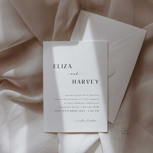 Peut inclure: Une carte d'invitation de mariage blanche avec du texte noir annon&ccedil;ant le mariage d'Eliza et Harvey. L'invitation comprend la date, l'heure et le lieu de la c&eacute;r&eacute;monie de mariage. Le texte indique "Eliza et Harvey, avec leurs familles, vous prient de bien vouloir les honorer de votre pr&eacute;sence &agrave; leur c&eacute;l&eacute;bration de mariage Bendenler Estate | Berrima NSW 16 septembre 2023 | 16h00 r&eacute;ception &agrave; suivre"