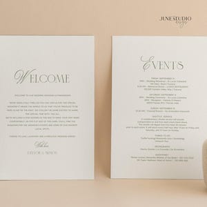 May include: Two ivory wedding invitation cards with elegant script. One card says "Welcome" and the other lists "Events" with a detailed schedule. The cards are on a neutral background, with a small vase and decorative element.