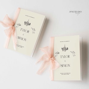 May include: Two ivory wedding ceremony programmes with a pink ribbon tied around each. The programmes feature a black and white illustration of a chandelier and two cherubs. The text on the programmes reads "Welcome to the wedding of Tyler & Simon".