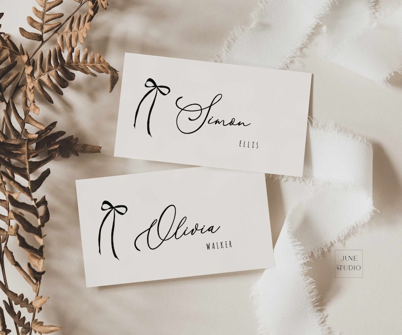 May include: Two white cards with black calligraphy names and a simple black bow design. The top card reads "Simon Ellis" and the bottom card reads "Olivia Walker".
