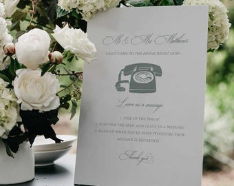 May include: A white rectangular sign with grey text and a grey rotary phone icon. The text reads: Mr & Mrs Matthew's, CAN'T COME TO THE PHONE RIGHT NOW..., Leave us a message, 1. PICK UP THE PHONE, 2. WAIT FOR THE BEEP, AND LEAVE US A MESSAGE.