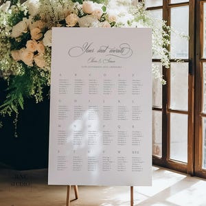 Könnte beinhalten: Ein weißes Hochzeitssitzplan-Schild auf einer Holzstaffelei mit dem Text Your seat awaits, Olivia & Simon, 16th September 202X | Berrima und einem Raster von Gästenamen, die alphabetisch von A bis Z in dunkelgrauer serifenloser Schrift stehen.
