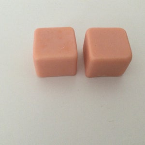 Puede incluir: Dos pequeñas pastillas de cera fundente de color rosa claro.