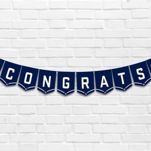 May include: A navy blue banner with white letters spelling "CONGRATS" and a white Air Force logo on each end.