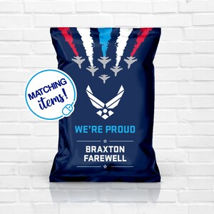 May include: Blue and white chip bag with a red, white, and blue star design. The bag has the text "WE'RE PROUD" and "BRAXTON FAREWELL" printed on it. The bag also has a blue Air Force logo with a star in the center.
