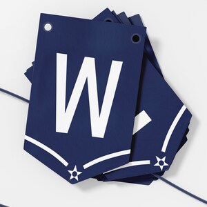 May include: A navy blue banner with a white star and the letter "W" in white. The banner is folded and has a hole at the top for hanging.