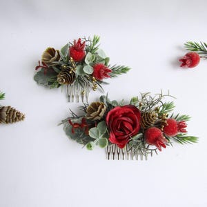 May include: Two floral hair combs with red roses, berries, and pinecones. The combs feature a mix of green and brown foliage, creating a festive and natural look. Perfect for weddings or holiday events.