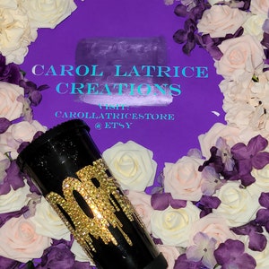 May include: Black tumbler with a gold glitter design that says "30" with gold glitter dripping down the side. The tumbler is surrounded by white and purple flowers.