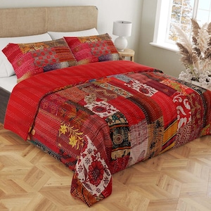 Könnte beinhalten: Rote und weiße Patchwork-Decke mit Blumenmuster. Die Decke besteht aus verschiedenen Stoffen und ist ein wunderschönes Beispiel für indisches Handwerk.