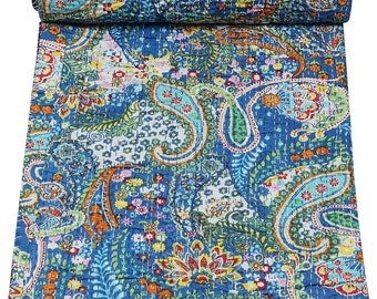 Puede incluir: Un edredón enrollado y cosido a mano con un vibrante estampado de cachemira. El edredón presenta un rico fondo azul con diseños intrincados en tonos de verde azulado, naranja, amarillo y blanco. Las costuras detalladas añaden textura e interés visual al textil.