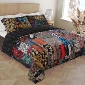 Può includere: Un piumone patchwork nero e multicolore con una varietà di motivi e trame. Il piumone è su un letto con cuscini a motivi neri e bianchi.