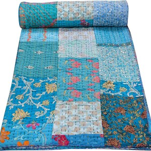 Puede incluir: Una colcha de retazos con fondo azul y motivos florales. La colcha está hecha de diferentes telas y colores, incluyendo rosa, blanco y dorado. La colcha está cosida a mano y tiene un aspecto vintage único.