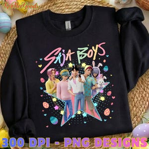 May include: Black sweatshirt featuring a colorful graphic of anime-style characters and the text "Saja Boys." The design includes stars, Easter eggs, and a bunny. The sweatshirt is a crew neck style.