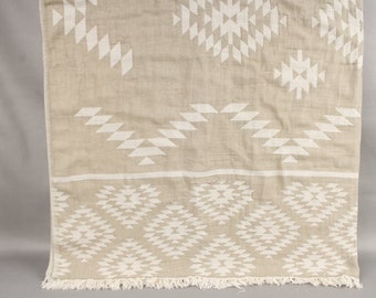 May include: Beige and white patterned textile with a geometric design. The fabric features repeating white diamond and triangle shapes on a beige background. The bottom edge has a fringe.