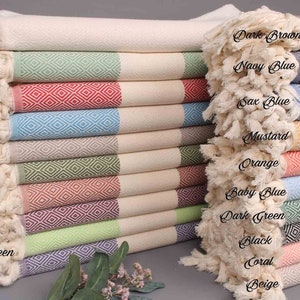 May include: A stack of Turkish towels in various colours, including natural, green, red, turquoise, brown, khaki green, brick, damson, pistachio green, purple, dark brown, navy blue, sax blue, mustard, orange, baby blue, dark green, black, coral, and beige. Each towel features a diamond pattern.