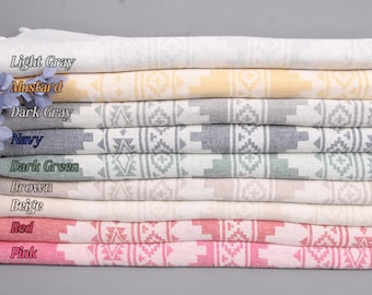 May include: A stack of eight folded cotton towels in various colors, including light gray, mustard, dark gray, navy, dark green, brown, beige, red, and pink. Each towel features a geometric pattern and fringed edges.