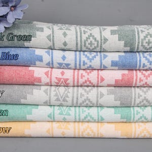 Pode incluir: Uma pilha de seis toalhas turcas dobradas em v&aacute;rias cores: verde escuro, azul sax, vermelho, cinza, verde e amarelo. Cada toalha apresenta um padr&atilde;o geom&eacute;trico branco e uma borda com franjas. As cores est&atilde;o rotuladas na imagem.