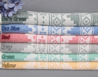 May include: A stack of six folded Turkish towels in various colors: dark green, sax blue, red, gray, green, and yellow. Each towel features a geometric pattern in white and has a fringed edge. The colors are labeled on the image.