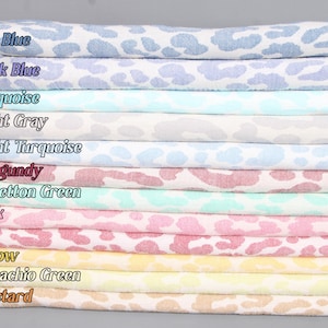 Pode incluir: Um conjunto de 12 amostras de tecido com um padrão de estampa de leopardo em várias cores, incluindo azul saxo, azul escuro, turquesa, cinza claro, turquesa claro, bordô, verde benetton, rosa, vermelho, amarelo, verde pistache e mostarda.