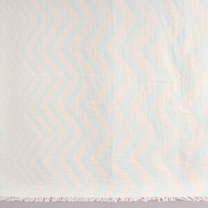 May include: A light blue and white chevron patterned beach towel with a fringed edge. The towel is made of a soft, lightweight material, perfect for the beach or pool. The design features a repeating zigzag pattern.