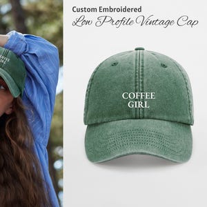 Puede incluir: Gorra vintage verde de perfil bajo con el texto bordado "COFFEE GIRL". La gorra está hecha de un material suave y desgastado. La imagen también muestra a una persona que lleva la gorra.