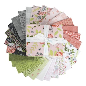 May include: A collection of fabric squares in various floral and geometric patterns, arranged in a circular fan shape. The color palette includes pink, green, gray, and white. The fabric is tied with a white ribbon that has the text "pure and delight".