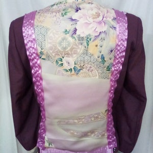 May include: A dark purple blazer with a floral patterned back panel. The back panel features a large peony flower design in shades of purple, pink, and cream. The blazer has purple ribbon detailing down the back and around the cuffs.