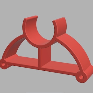 May include: A 3D-rendered red plastic object, possibly a bracket or holder. It features a curved top section and two arched side supports, connected by a central vertical piece and a flat base. The design includes rounded edges and circular holes.