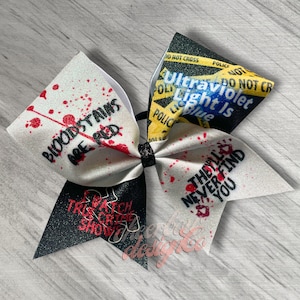 May include: A white and black cheer bow with red blood splatter. The white side has the text "Bloodstains are red" and "Watch True Crime Shows". The black side has the text "Ultraviolet Light Is Blue" and "They'll Never Find You".