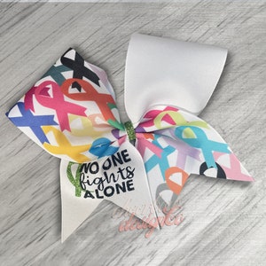 May include: A white cheer bow with a colorful ribbon design featuring multiple ribbon shapes and the text "No one fights alone".