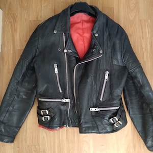 May include: Black leather motorcycle jacket with a red lining and multiple zippered pockets.
