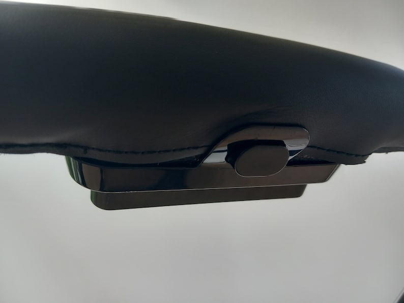 May include: A black leather armrest with a black plastic release button.