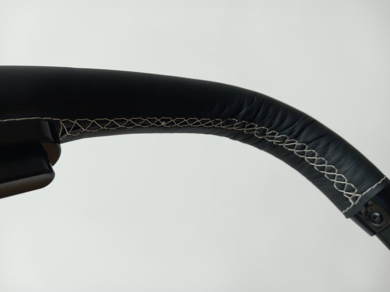 Op de afbeelding: Close-up van een zwart lederen stuurwiel met witte stiksels.