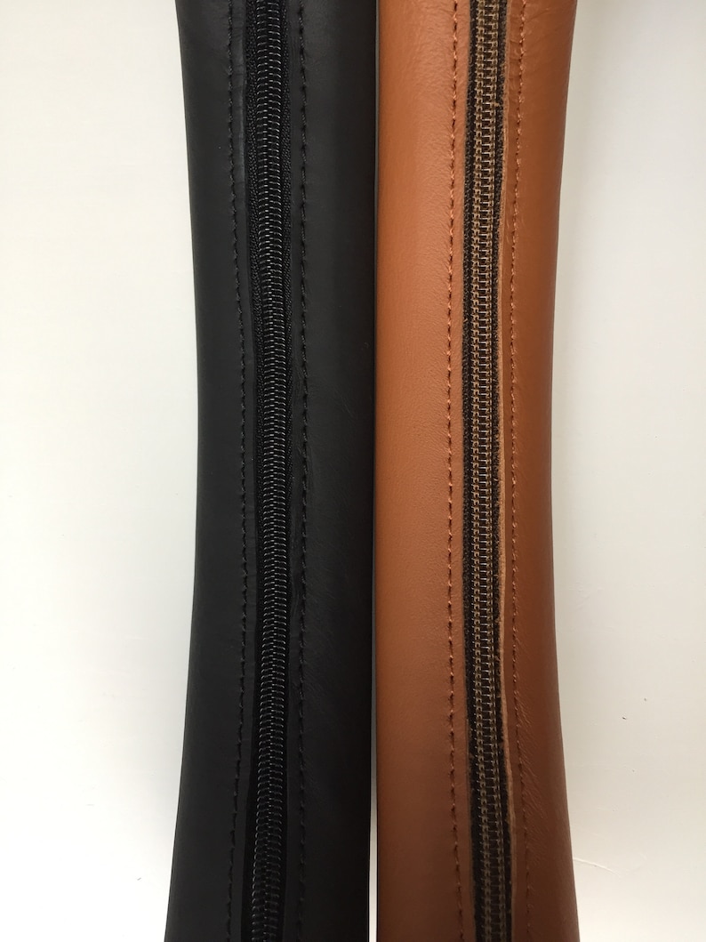 May include: Two zippered leather pouches, one black and one brown. Both pouches are closed and have a zipper running down the centre.