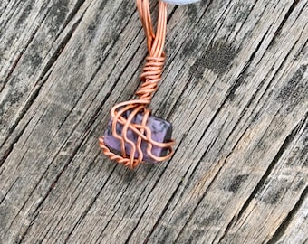 May include: A copper wire wrapped pendant featuring a square-shaped purple and gray stone.