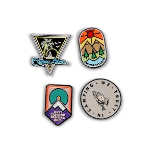 May include: Four embroidered patches with different designs. The first patch is a triangle with a palm tree, a tent, and the text "Campo Libre". The second patch is a rounded rectangle with a mountain range, a sun, and the text "Go West Get Lost". The third patch is a purple, orange, and teal patch with a mountain and the text "Anti Camping Club". The fourth patch is a circle with a praying hand and the text "Camping We Trust In".