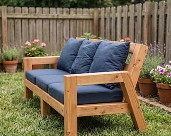 May include: A wooden outdoor sofa featuring a natural light brown finish with a sturdy frame and thick, dark blue cushions. The seating area includes three matching back cushions and three seat cushions, all in a solid dark blue fabric.