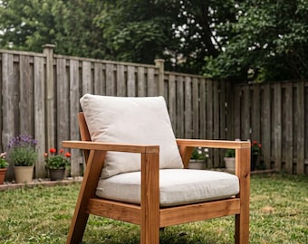 May include: A wooden armchair featuring a natural brown finish with straight, angular lines. The chair includes a thick, square back cushion and a matching seat cushion, both upholstered in a plain, light beige fabric for seating comfort.