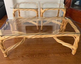 May include: Three glass-top tables with twisted rattan bases. The tables are arranged in a nested set, with the largest table in the front and the two smaller tables behind it.