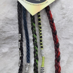 May include: Five braids of human hair with silver beads. The braids are black, blue, green, black and green, and red and black.