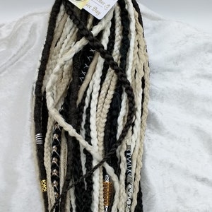 May include: A set of black, white, and beige synthetic dreadlocks with gold and silver beads. The dreadlocks are tied together with a tag that says "You Order # Ice Day".