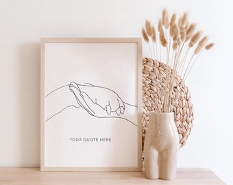 May include: A framed black and white line drawing of two hands holding each other. The drawing is on a white background and the frame is light wood. The text "YOUR QUOTE HERE" is printed below the drawing. A vase with a beige, textured, human-shaped design holds a bouquet of dried beige grass. The vase is sitting on a light wood surface.