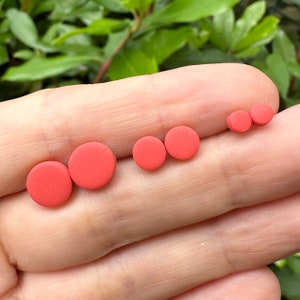 May include: A set of four red round stud earrings in different sizes.