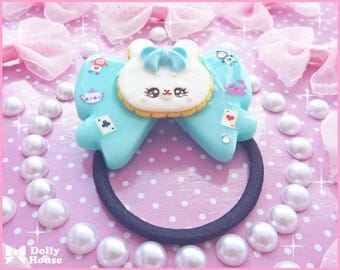 May include: A blue and white Alice in Wonderland themed hair scrunchie with a white bunny face and a black elastic band.