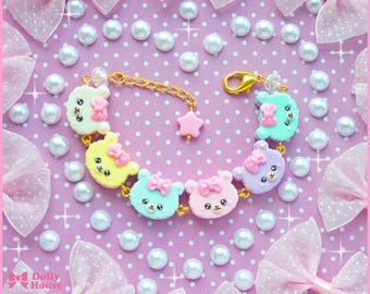 Puede incluir: Un brazalete de colores pastel con un dije de estrella y seis dijes de osos con lazos. Los osos son en tonos de rosa, amarillo y azul.