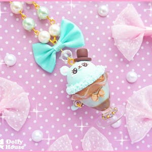 May include: A pastel green and brown ice cream cone charm with a cute bunny face and a tiny top hat. The charm is attached to a necklace with pastel green and white beads.