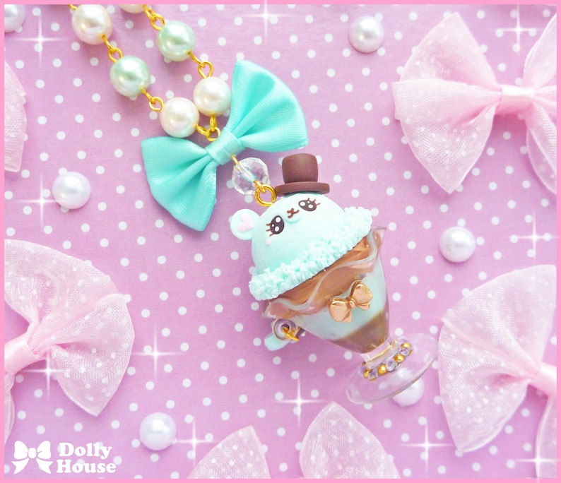 May include: A pastel green and brown ice cream cone charm with a cute bunny face and a tiny top hat. The charm is attached to a necklace with pastel green and white beads.