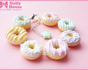May include: A bracelet featuring colourful donut charms. The donuts are decorated with sprinkles, stripes and frosting in shades of pink, blue, yellow and green. The bracelet has a silver chain and a star charm.
